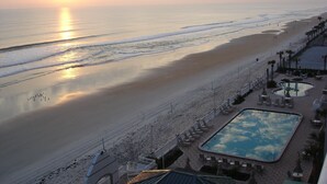 Blick auf einen Strand mit einem Poolbereich, einschließlich Liegestühlen und Sonnenschirmen.