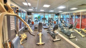 Et fitnesscenter med forskellig træningsudstyr, herunder løbebånd, spinningcykler og styrkemaskiner.
