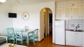 Eine kleine Küche mit weißen Schränken, einer eingebauten Spüle und einem Kühlschrank.