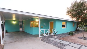 Een turquoise gebouw met een overdekte ingang en een klein voortuintje.