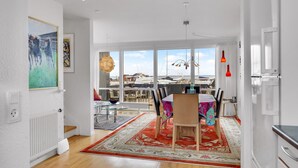 A dining area with a table, chairs, and a view of the sea through large windows. - 2 bedroom gorgeous home in Tranekær (Tranekær)