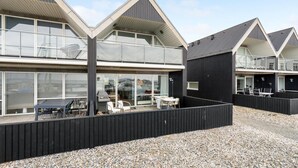 A modern building with a black exterior and white trim, featuring large windows and a balcony area with outdoor seating. - 2 bedroom gorgeous home in Tranekær (Tranekær)
