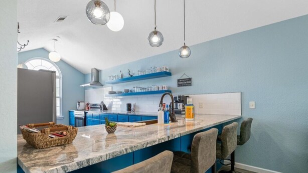 Eine moderne Küche mit blauen Schränken, einer Marmorarbeitsplatte und Barhocker.