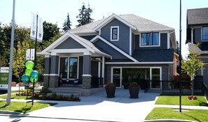 A modern two-story house with a covered front porch, large windows, and a garage. - Sunshine house_walkout south face suite (Surrey)