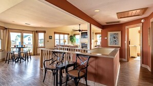 A spacious kitchen with a central island, wooden flooring, and a dining area with chairs and a table.