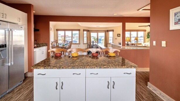A kitchen with granite countertops, white cabinets, and a stainless steel refrigerator.