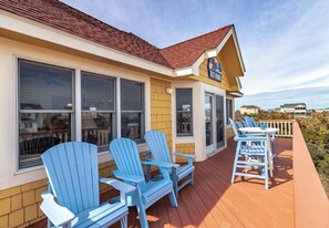 A building with a porch featuring blue Adirondack chairs and a table.
