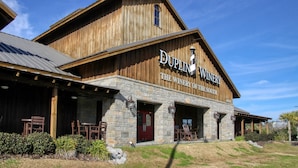 Un bâtiment en bois avec une enseigne indiquant « DUPLIN WINERY », des piliers en pierre et des places assises à l’extérieur.