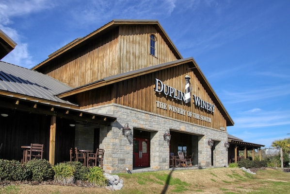 A wooden building with 'DUPLIN WINERY' signage, stone pillars, and outdoor seating.