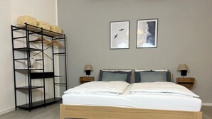 A bedroom with a wooden bed, two bedside tables with lamps, a black metal shelf unit, and two framed pictures on the wall. - Loft with wallbox, WLAN workstation, garage, for 3 people, 100 m to the Moselle (Traben-Trarbach)