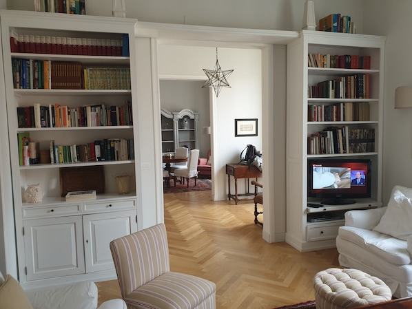 Una sala de estar con una amplia estantería, un televisor y un comedor.