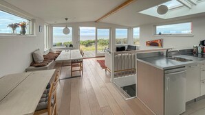 Uma cozinha moderna com uma ilha grande, área de jantar com vista e sala de estar espaçosa também com vista.