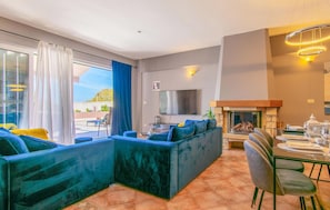 Relax in a spacious living area with a large sofa, flat-screen TV, and sliding glass door to an outdoor patio.