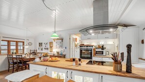 Ett rymligt kök med en stor köksö, träskåp och moderna vitvaror.