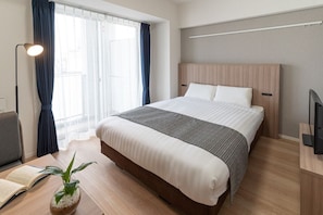 Una habitación de hotel moderna con una cama grande, un escritorio con silla, un televisor y una ventana con cortinas.