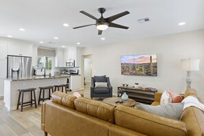 A modern kitchen with white cabinets, a central island, and a ceiling fan.