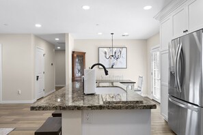A modern kitchen with a granite countertop, stainless steel appliances, and a pendant light.
