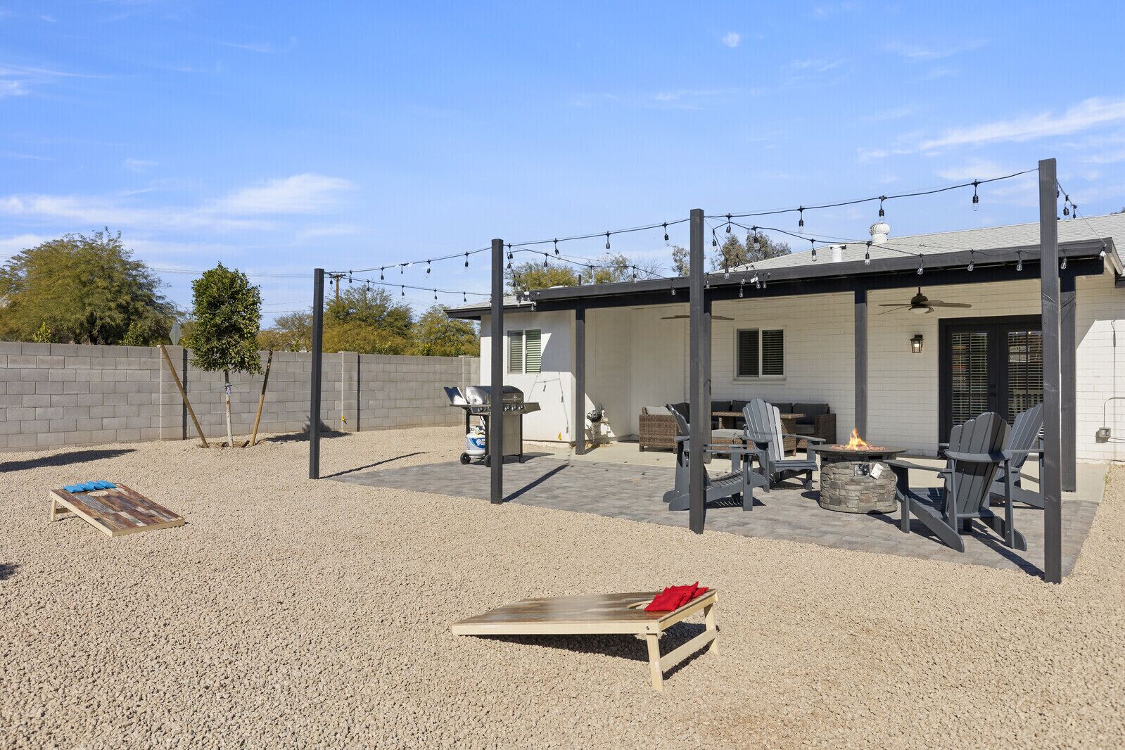 Un patio extérieur couvert, aménagé avec des sièges, un barbecue et un foyer.