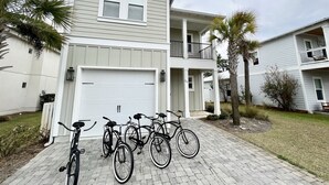 A two-story residential building with a garage, a balcony on the second floor, and bicycles parked in front. - Spacious, 4BR Beach Home with Golf Cart & Pool Access (Miramar Beach)