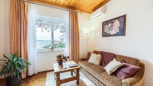 Un accogliente soggiorno con soffitto in legno, un divano con cuscini, un tavolino con un vaso di fiori e una pianta in vaso.
