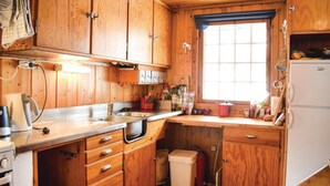Une cuisine de taille réduite, avec des meubles de rangement en bois, un évier, une cuisinière et une fenêtre.