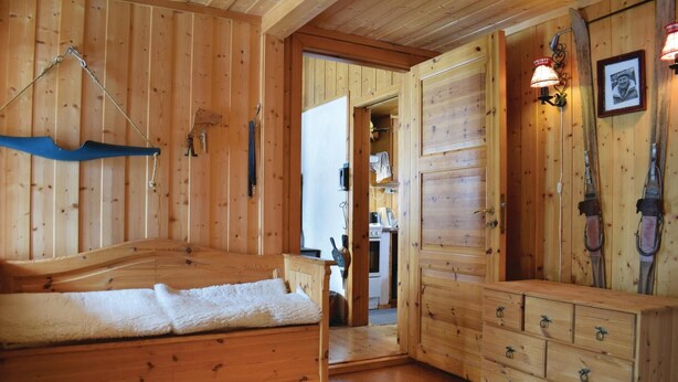 L’intérieur d’un chalet en bois, avec un lit, une commode et du matériel de ski.