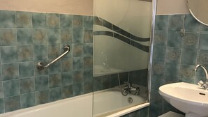 A bathroom with a bathtub, a glass-enclosed shower, and a sink with a mirror. - Beautiful apartment in the center of Anglet, 10 minutes from the beach (anglet)