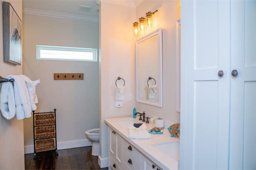 Une salle de bain avec un meuble-lavabo blanc, un grand miroir et un porte-serviettes.