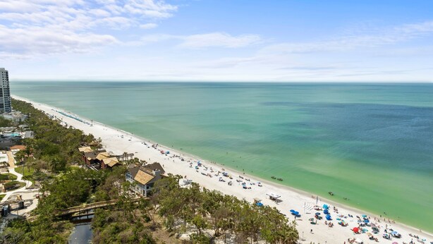 A beach with a long stretch of sand, a few buildings, and a clear view of the ocean. - The Fitz - Stylish 3Br, 2Ba with pool.  Walk to beach. Great views. (Naples)