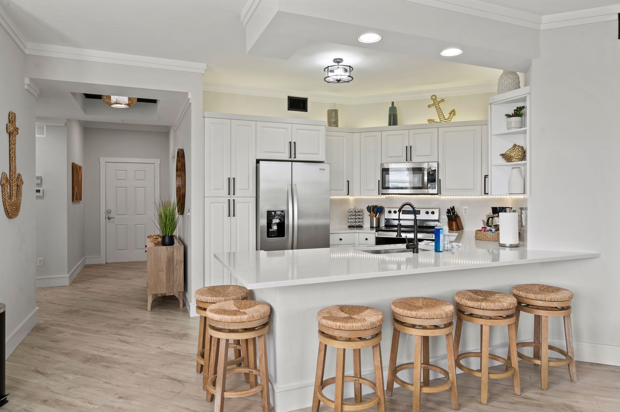 A modern kitchen with white cabinetry, stainless steel appliances, and a central island with bar stools.