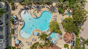 An aerial view of a resort with a large central pool, multiple smaller pools, and numerous sun loungers and umbrellas. - The Fitz - Stylish 3Br, 2Ba with pool.  Walk to beach. Great views. (Naples)