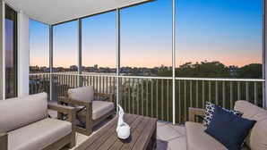 A balcony with a city view, wooden furniture, and a white decorative item. - The Fitz - Stylish 3Br, 2Ba with pool.  Walk to beach. Great views. (Naples)