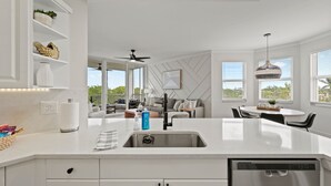 A modern kitchen with a central island, white cabinetry, and a built-in dishwasher. - The Fitz - Stylish 3Br, 2Ba with pool.  Walk to beach. Great views. (Naples)