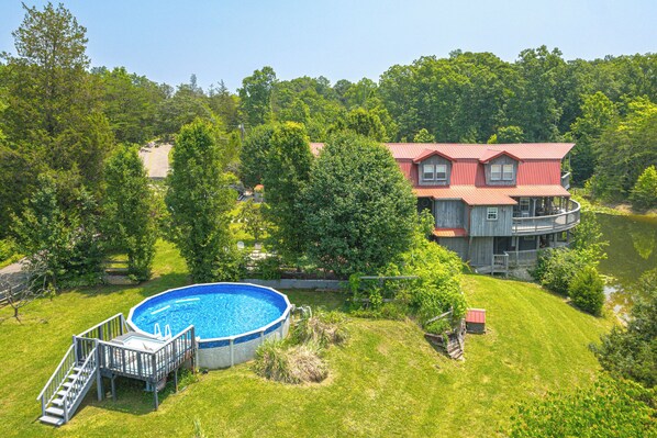 Une maison à deux étages avec un toit rouge et une grande piscine.