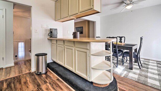 A compact kitchen with a central island, a dining area with a table and chairs, and a ceiling fan. - Maryland Vacation Home Near US Capital! (Riverdale Park)