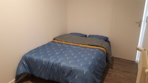 A bedroom with a bed, a window, and a door.