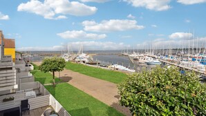 A marina with boats docked, a grassy area, and a building with outdoor seating. - Stunning apartment in Rudkøbing (Rudkøbing)