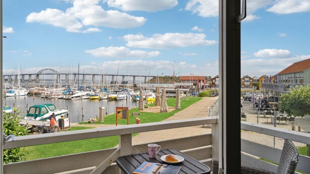 A balcony with a view of a marina, a bridge, and a row of houses. - Stunning apartment in Rudkøbing (Rudkøbing)