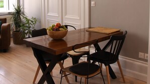 A dining area with a wooden table, black chairs, and a bowl of fruit. - Ligny garden (ST OMER)