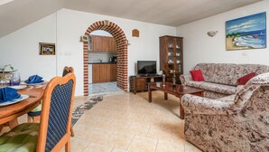 Un soggiorno con divano, televisore e zona pranzo con tavolo e sedie.
