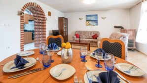 Un'area pranzo con un arco in mattoni che conduce a una cucina, un divano e un quadro appeso al muro.