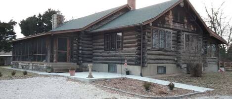 A log cabin with a sloped roof, large windows, and a chimney.