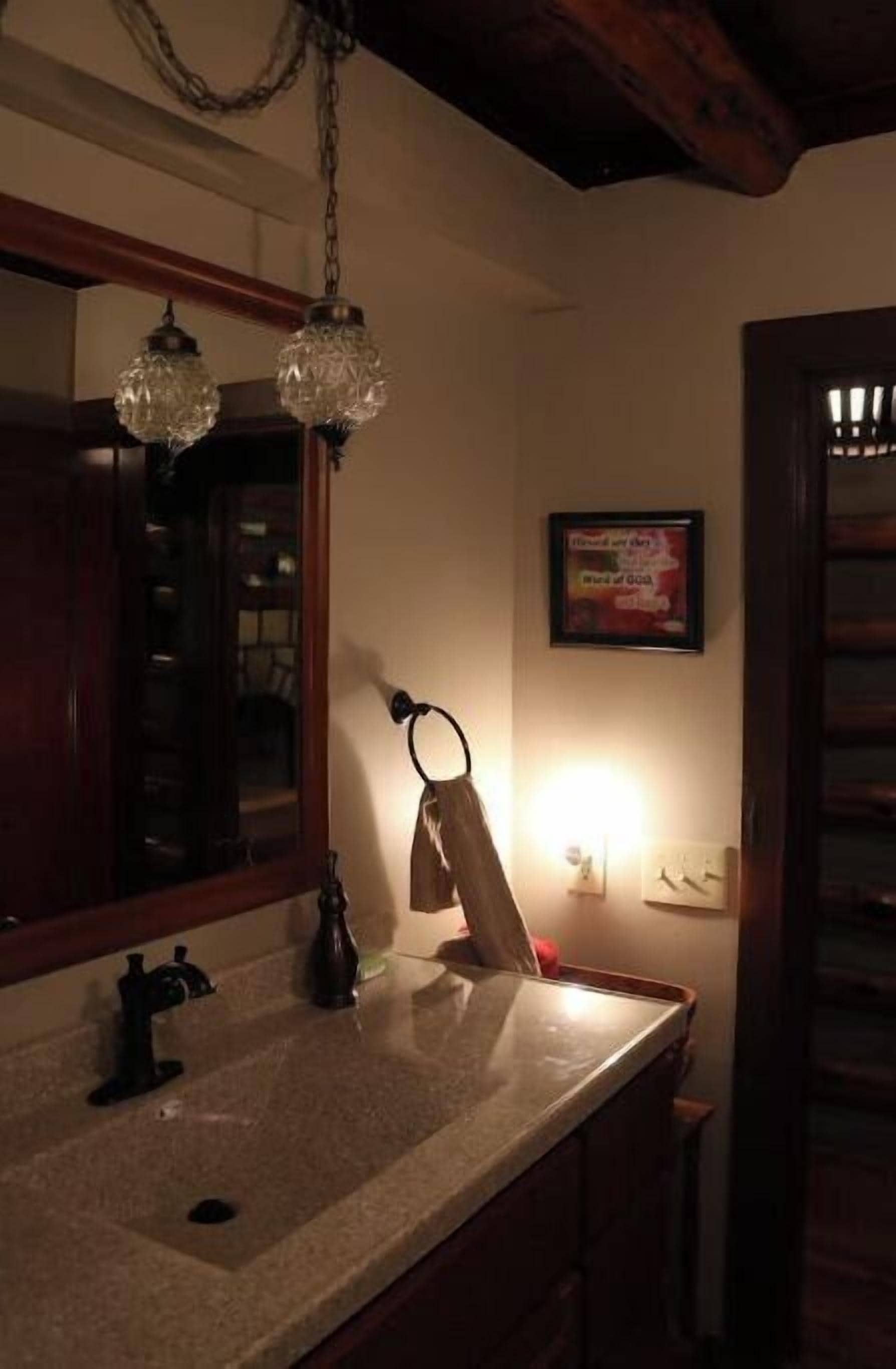 A bathroom with a sink, mirror, and hanging light fixture.