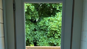 A door leading to a wooden deck with outdoor furniture and a green hedge in the background. - Gorgeous Gem in Niagara’s Wine Country (Niagara Falls)