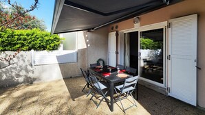 An outdoor patio with a table set for two, a covered seating area, and a sliding glass door. - Amazing home in Agde with outdoor swimming pool (Agde)
