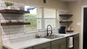 A modern kitchen with a large window, built-in shelves, and a stainless steel sink.