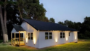 A single-story building with a sloped roof, a porch with a railing, and a small covered area with a staircase.