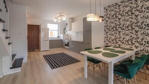 A modern kitchen with grey cabinets, a white refrigerator, and a dining area with a white table and green chairs. - Pet friendly home in Klodawa with sauna (Klodawa)