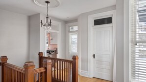 Una escalera con barandillas de madera que conduce a un cuarto con una puerta blanca y una ventana con persianas.