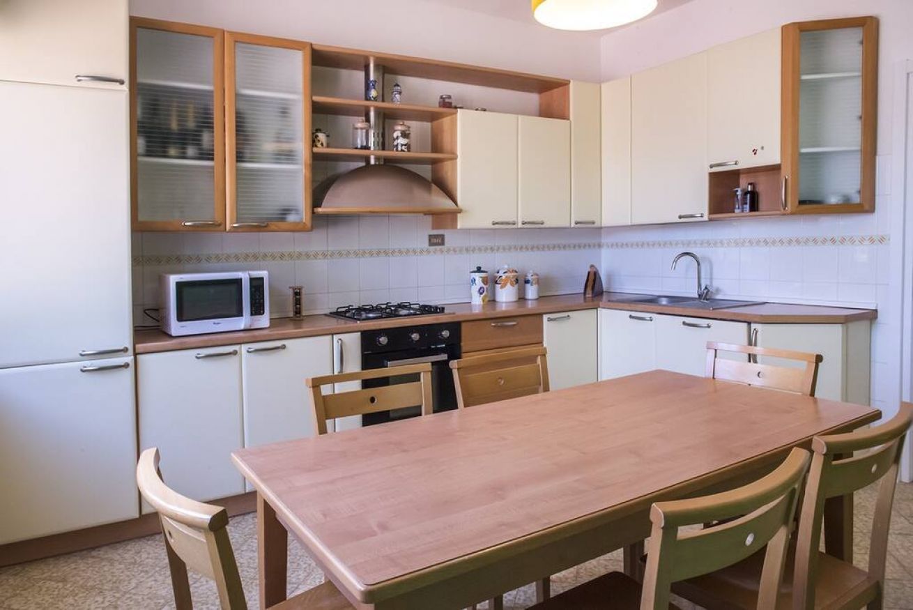 A compact kitchen with a microwave, stove, cabinets, and a dining table with chairs.